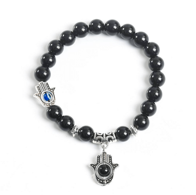 The Eye of Horus Bracelet-Health & Insight with black beads and Hamsa hand charms, symbolizing guardianship and healing, against a white background.