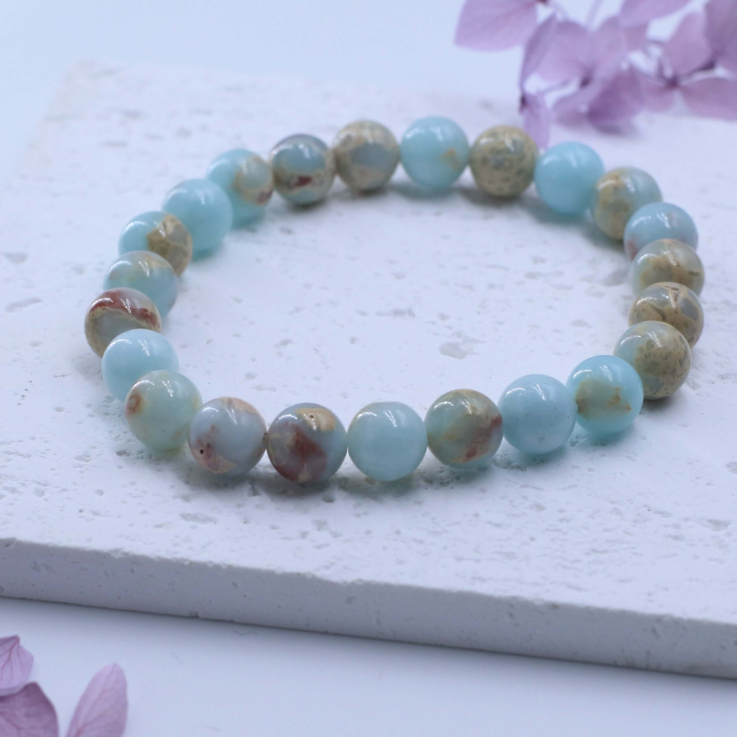 Charming Shoushan Stone Bracelet for Auspiciousness featured on a textured white surface with purple petals.