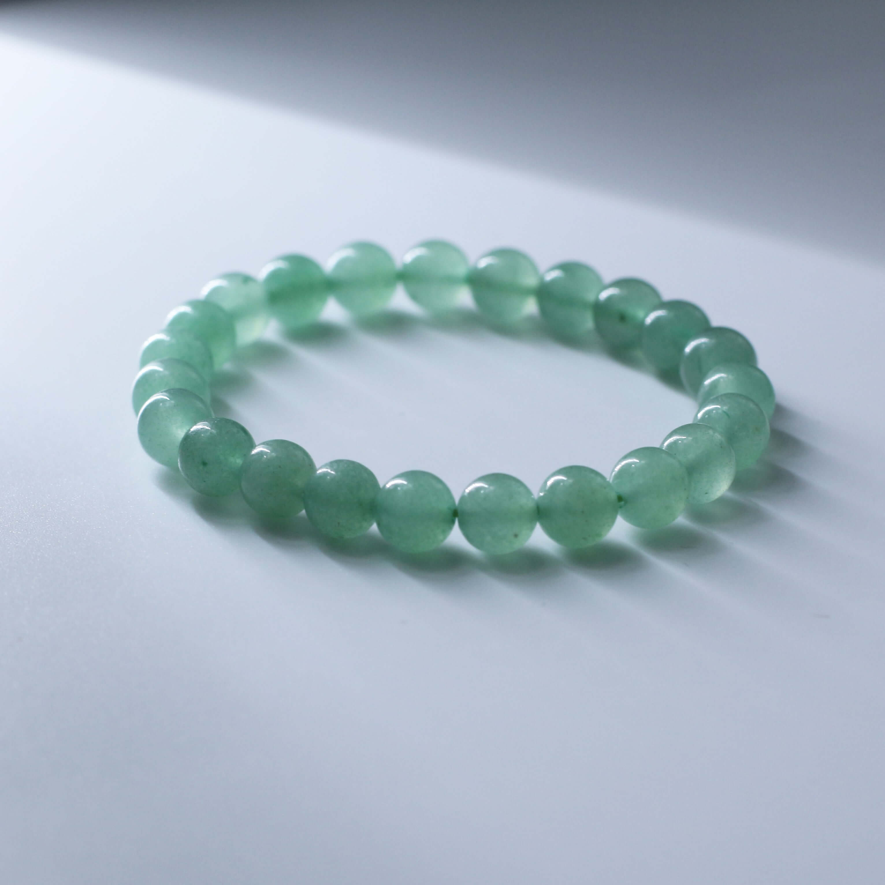 Natural Green Aventurine Bracelet on a white surface, promoting health and vitality with its crystal energy.