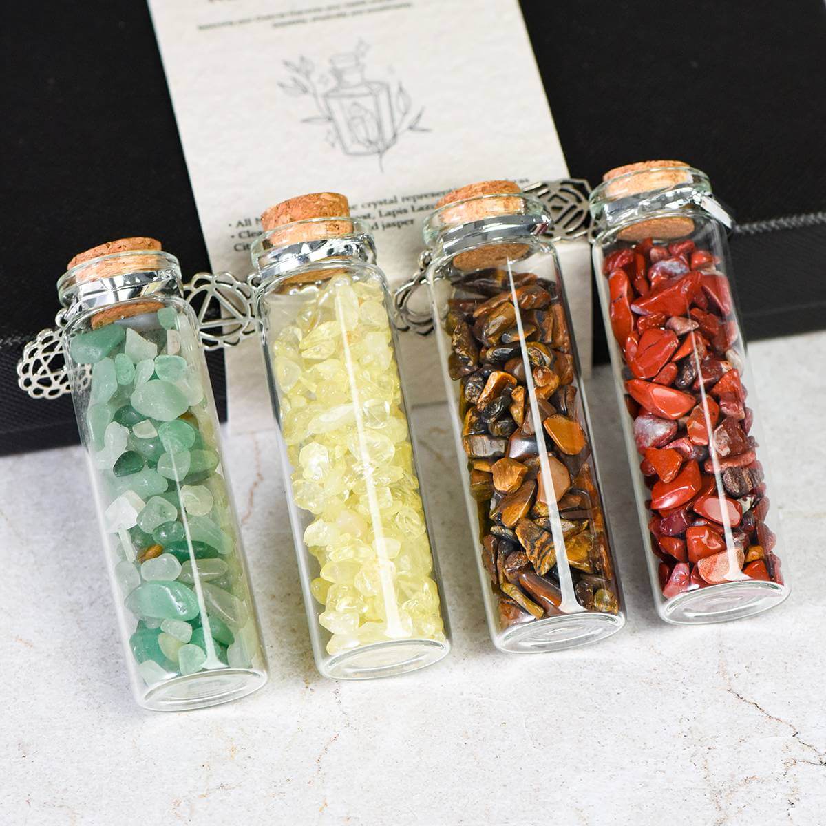 Four glass wish bottles with colorful healing stones, part of the 7 Chakra Wish Bottle Set for spiritual power and chakra connection.