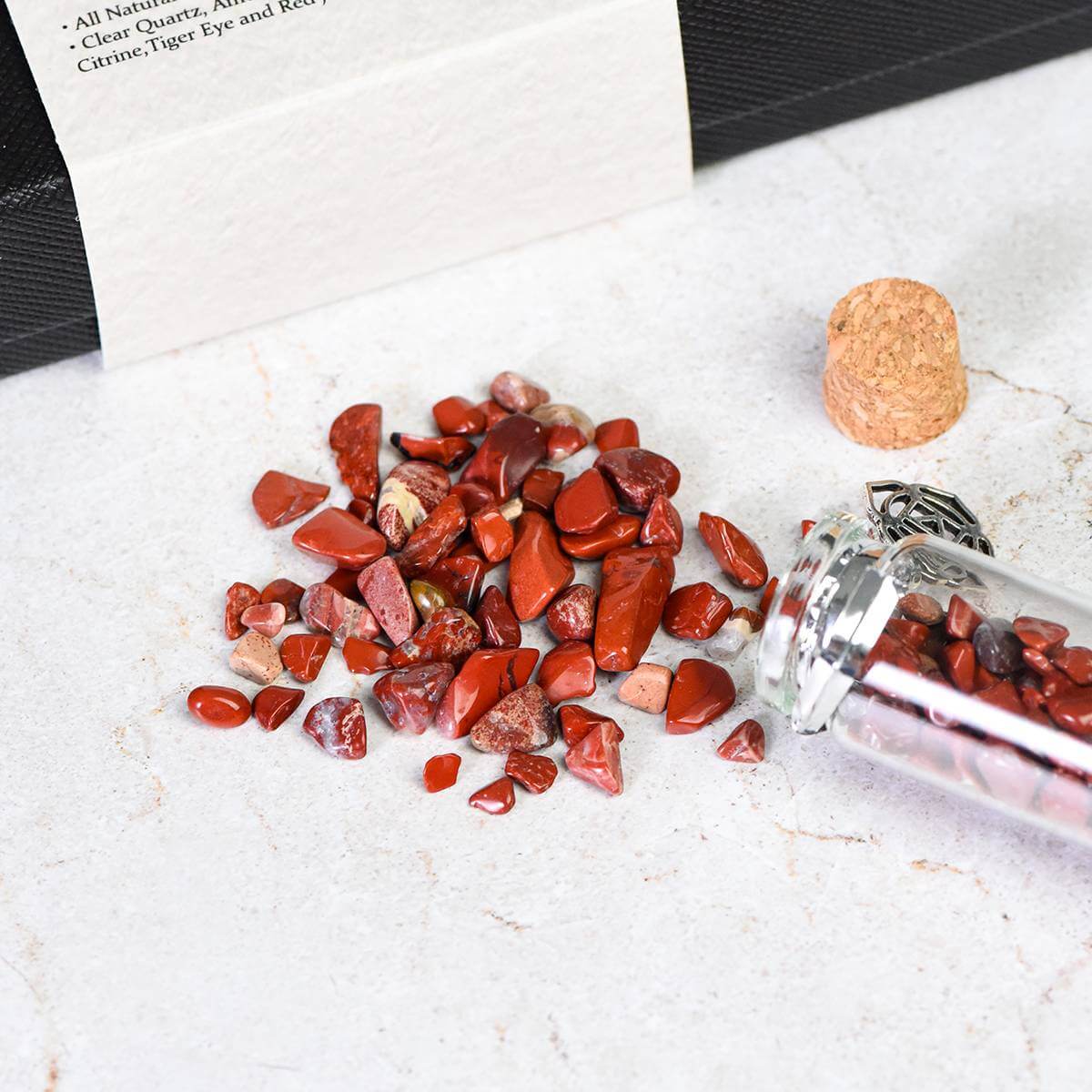 7 Chakra Wish Bottle with red stones spilled on a table, enhancing spiritual healing and energy alignment.