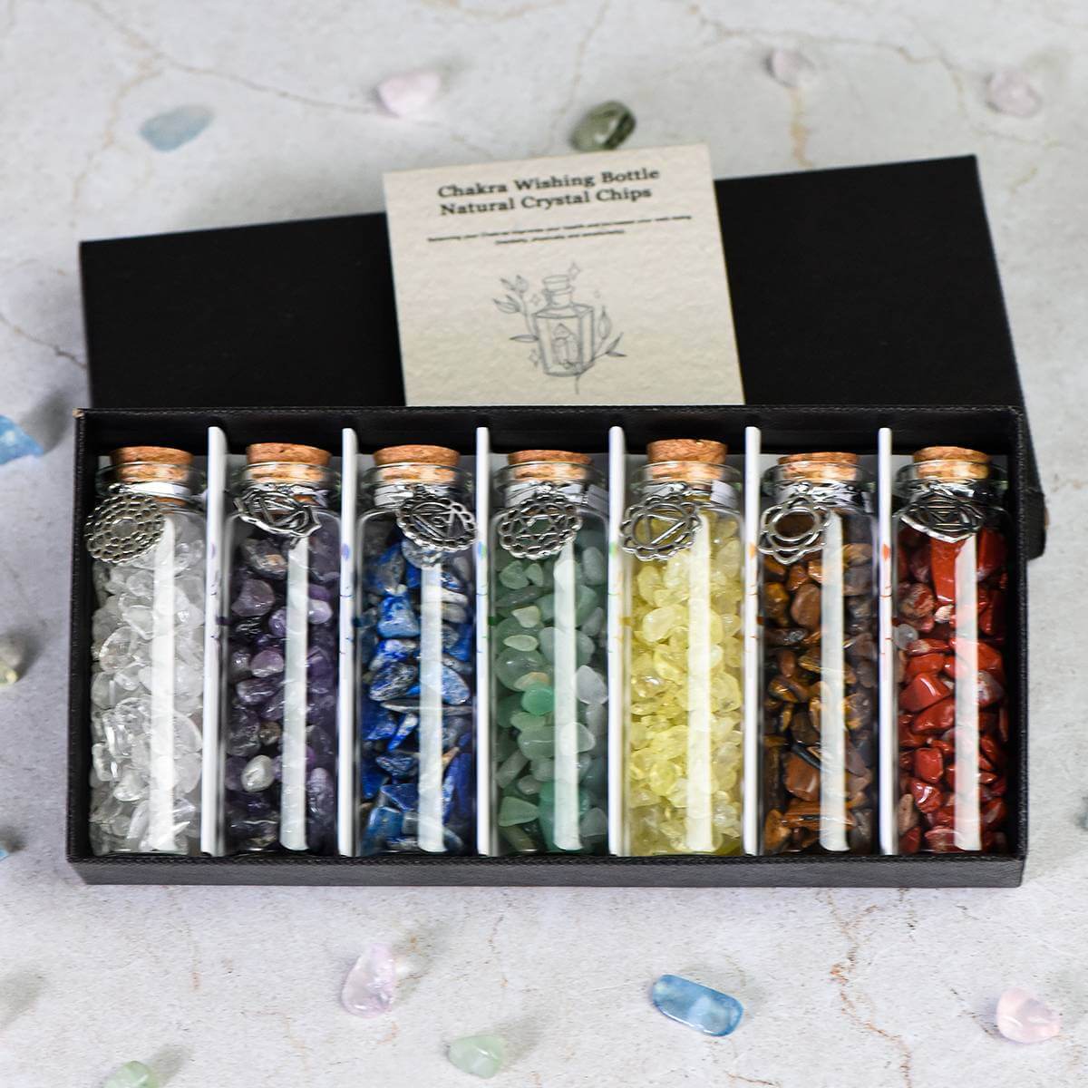 7 Chakra Wish Bottle Set with colored crystal chips for spiritual healing and chakra alignment, displayed in an open black box.