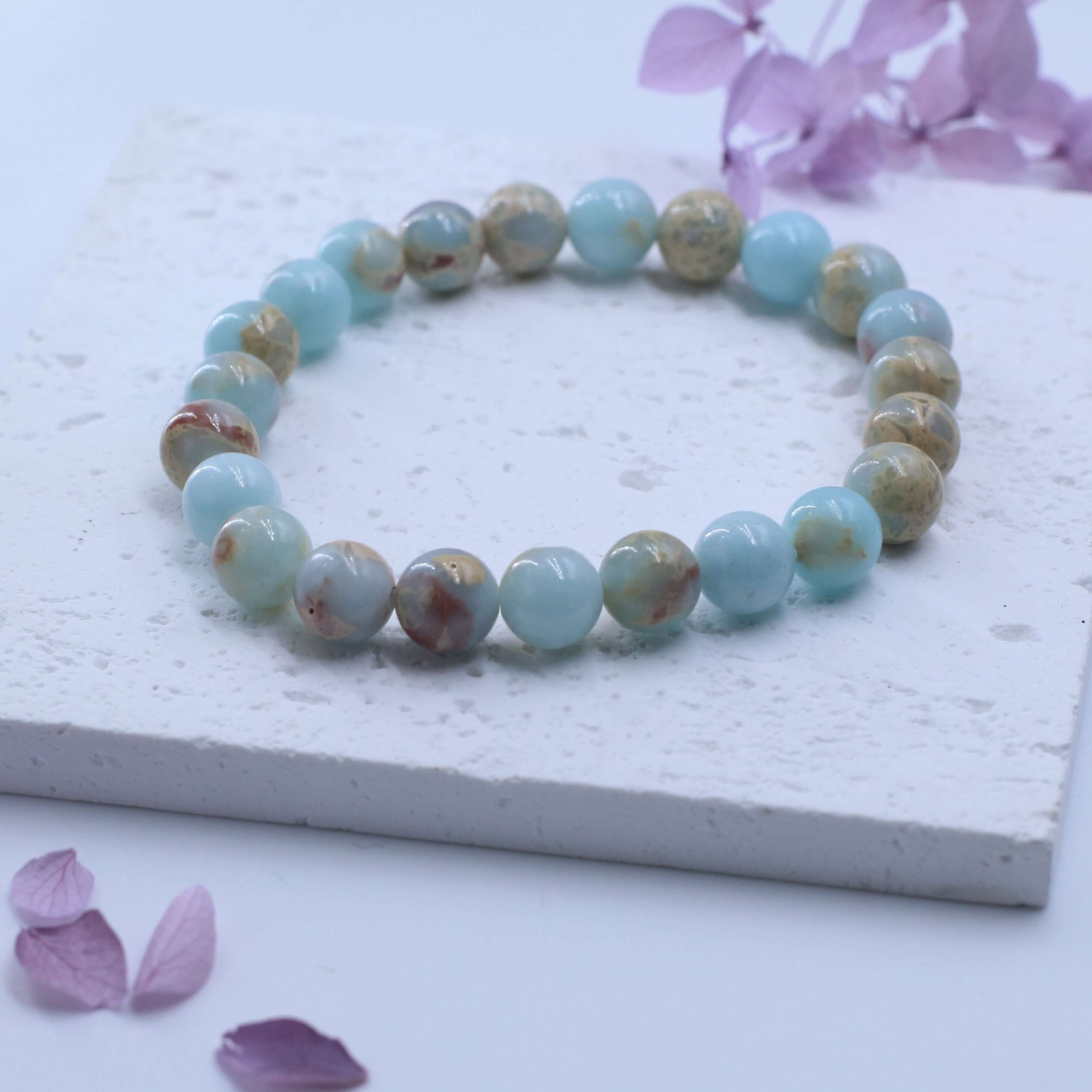 Charming Shoushan Stone Bracelet for Auspiciousness on white stone surface with purple petals