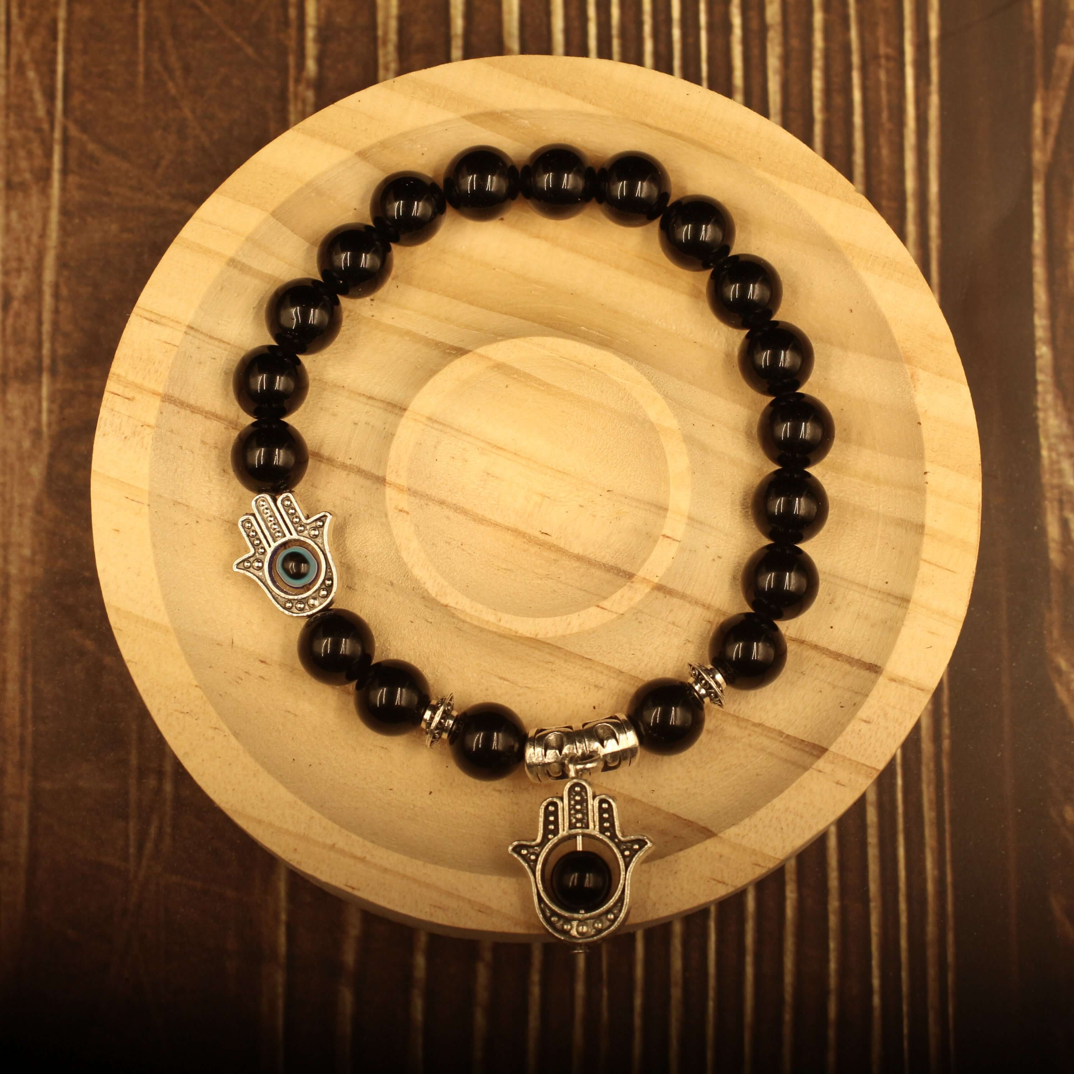 The Eye of Horus Bracelet-Health & Insight on a wooden display showcasing black beads and spiritual charms.