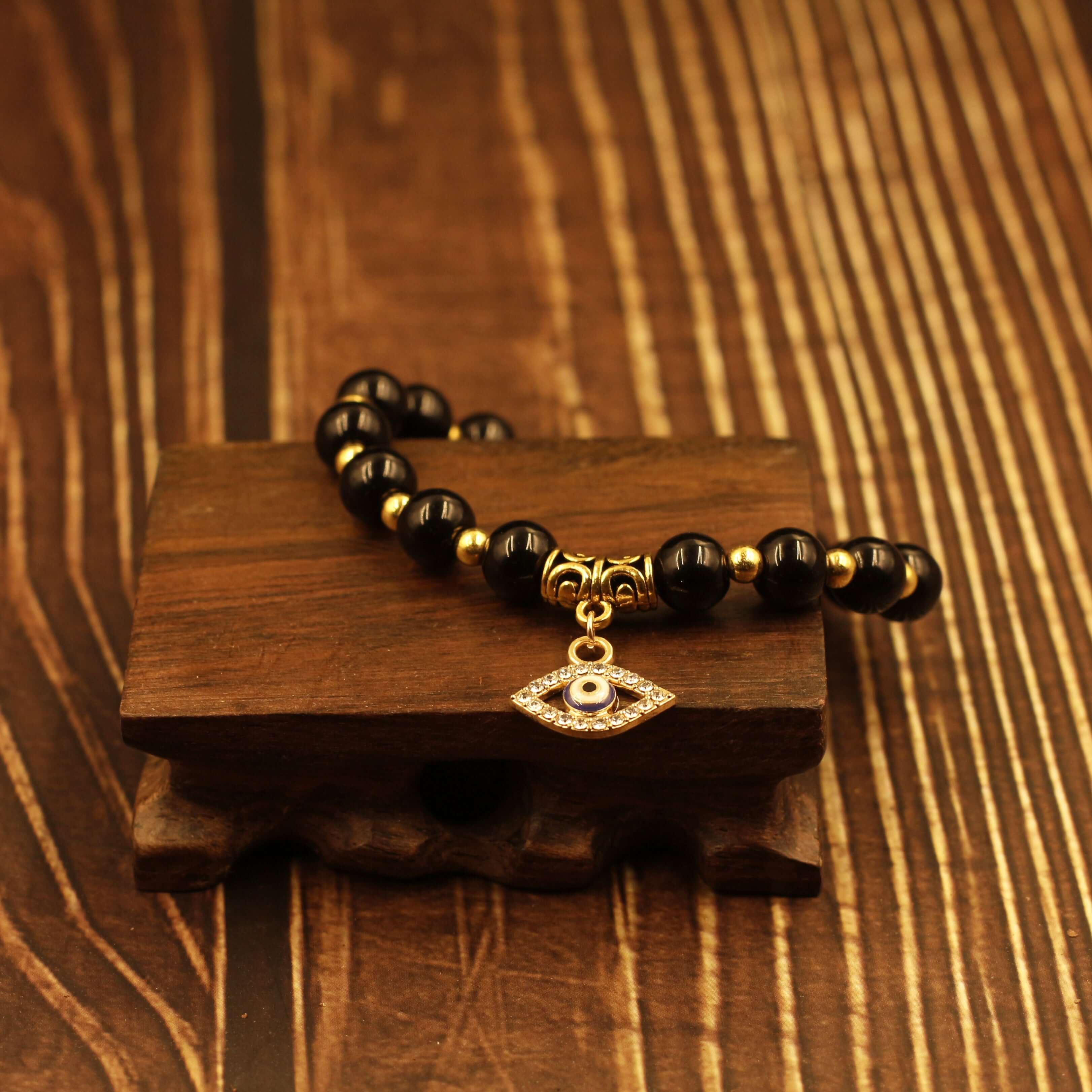 Evil Eye Bracelet-Protection with black beads and evil eye charm on wooden surface for warding off malicious influences.