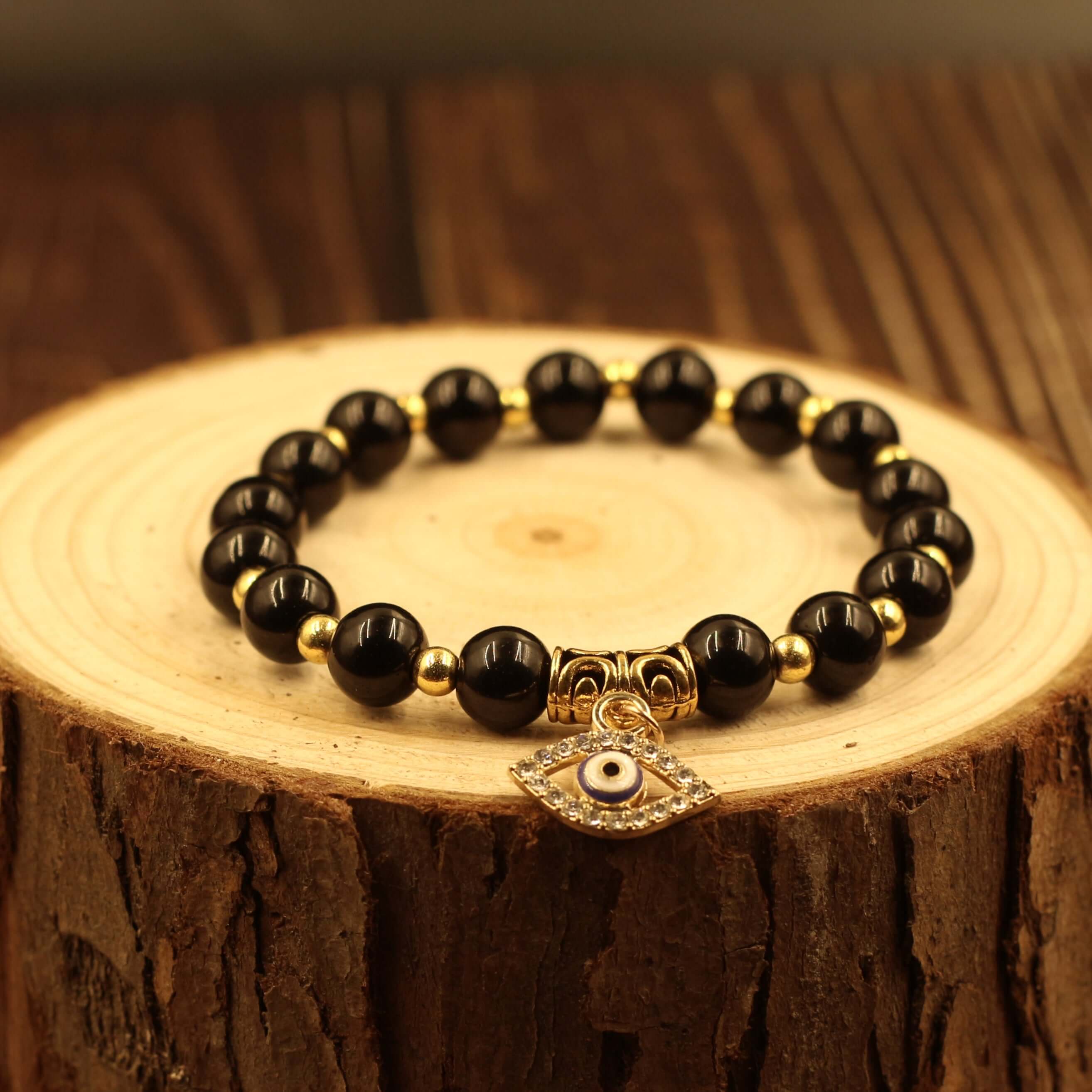 Evil Eye Bracelet-Protection with black beads and gold accents on wooden display, warding off evil gazes and bringing peace of mind.