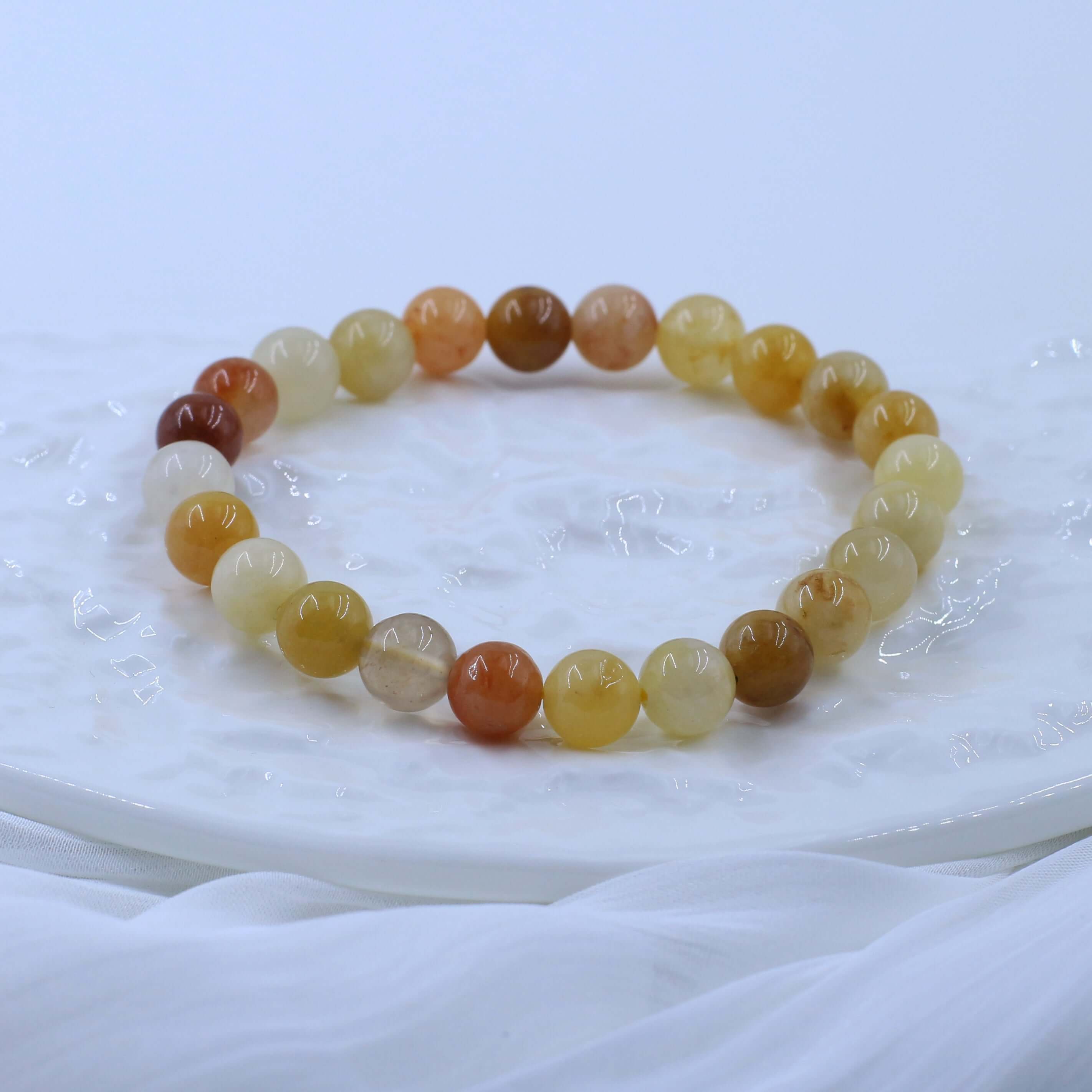 Noble Gold Silk Jade Bracelet promoting wealth with high-quality golden beads on a white surface.