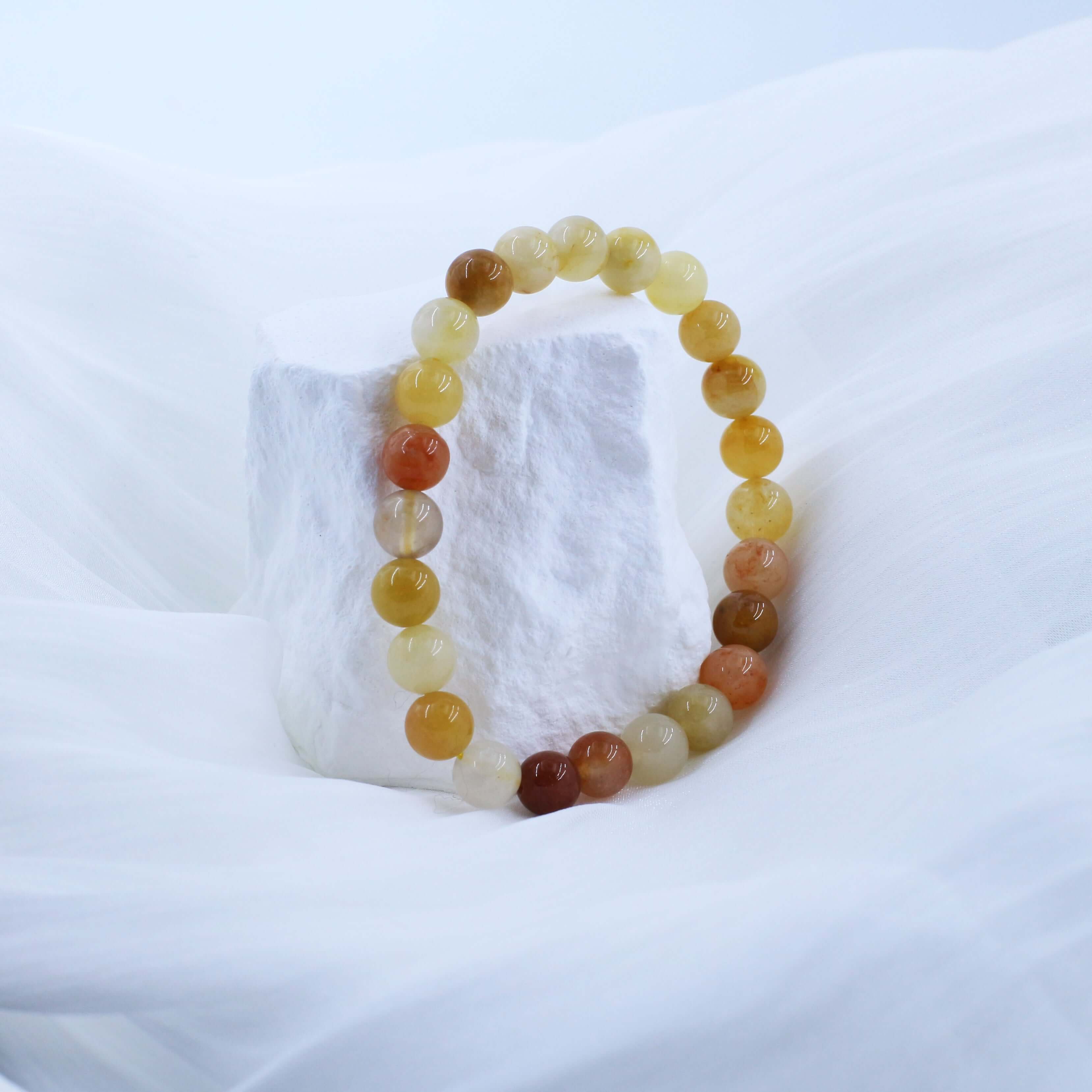 Gold Silk Jade Bracelet on white fabric enhancing wealth and prosperity.