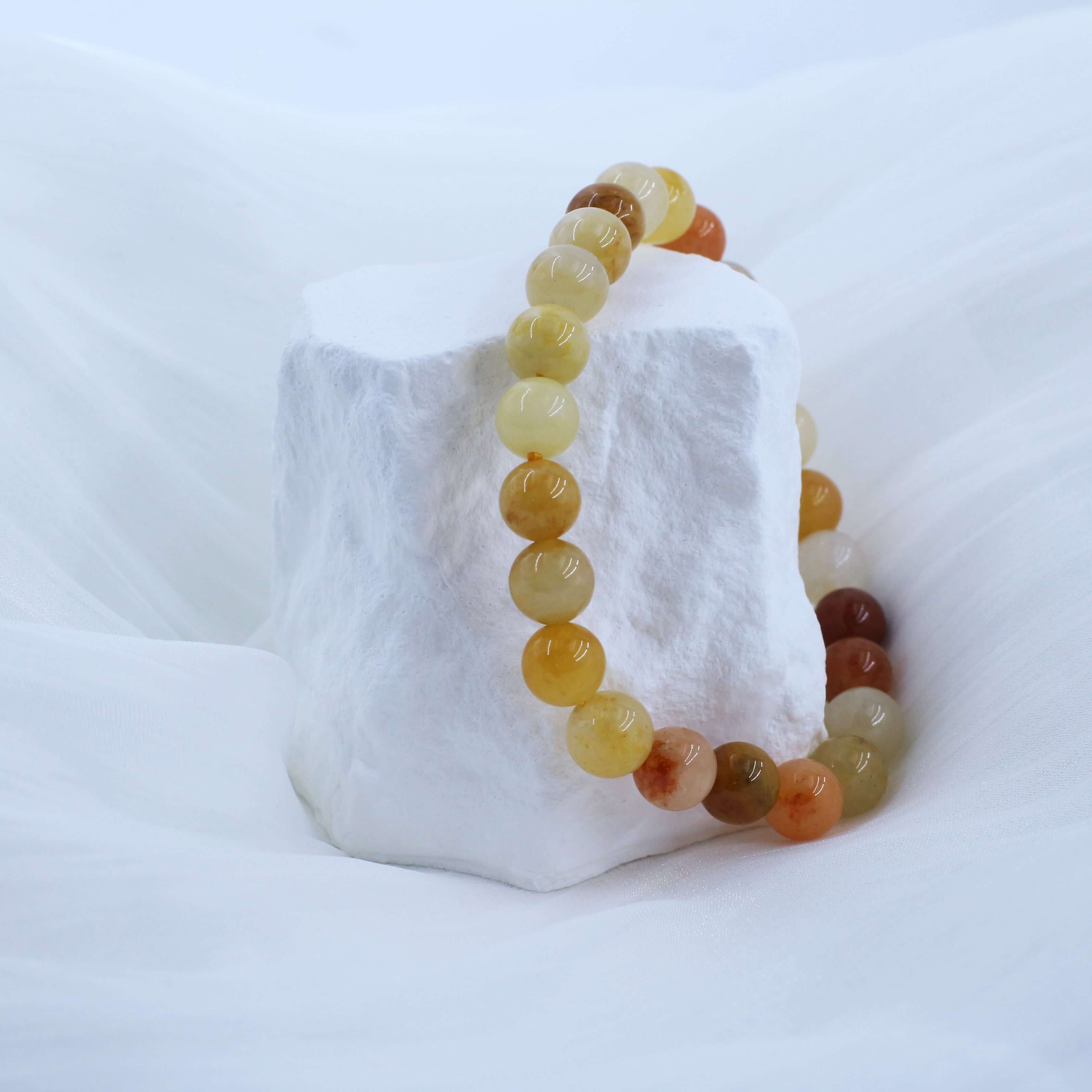 Noble Gold Silk Jade Bracelet featuring high-quality beads promising wealth and prosperity, elegantly displayed on a white backdrop.