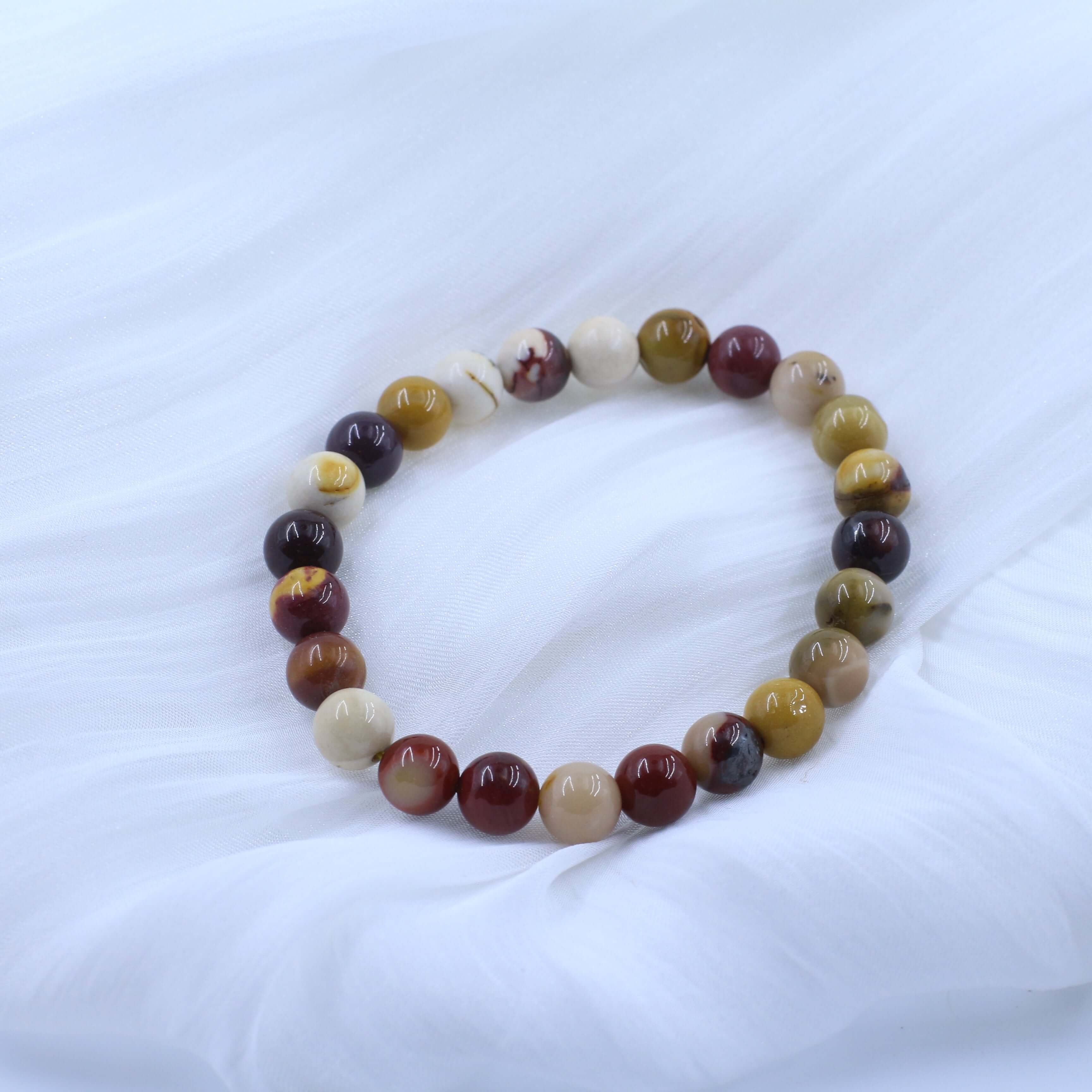 Warm Mookaite Bracelet for Confidence with vibrant, multicolored beads on a soft white fabric background.