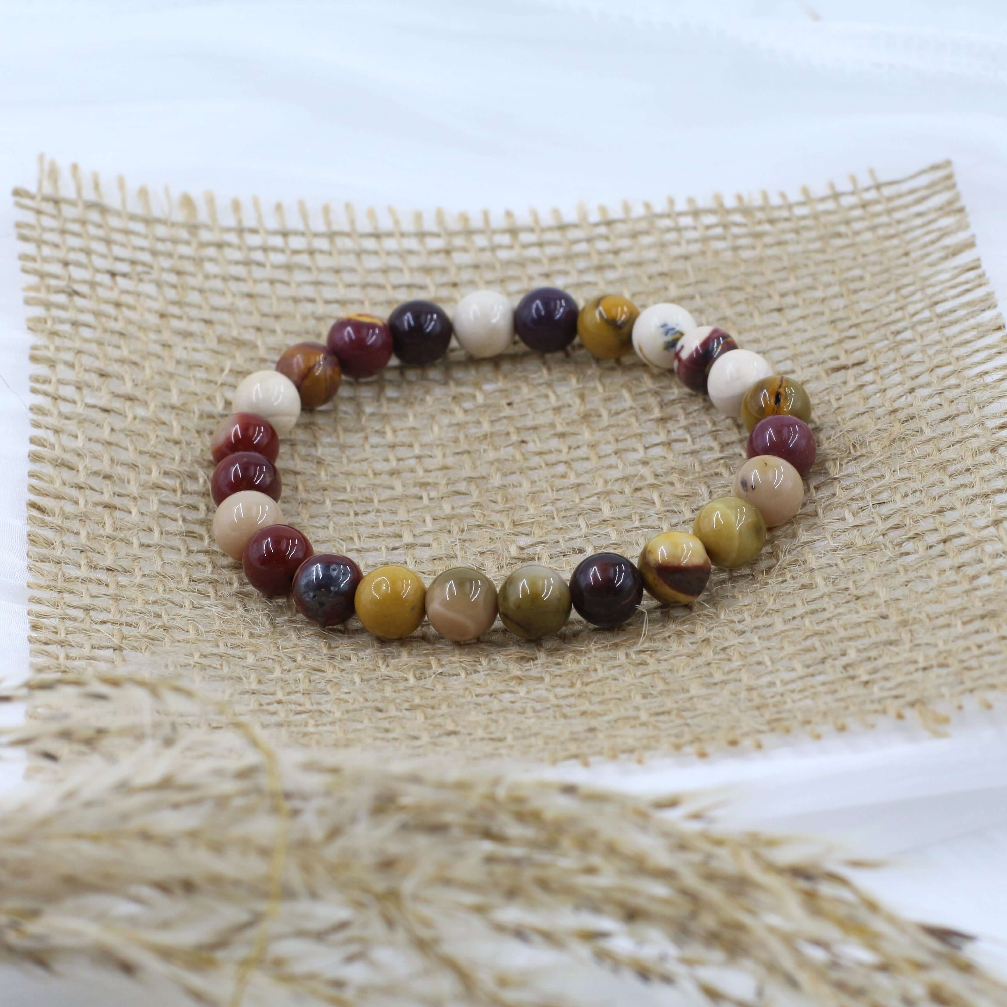 Warm Mookaite Bracelet for Confidence with multicolored beads on burlap mat, perfect for spiritual empowerment.